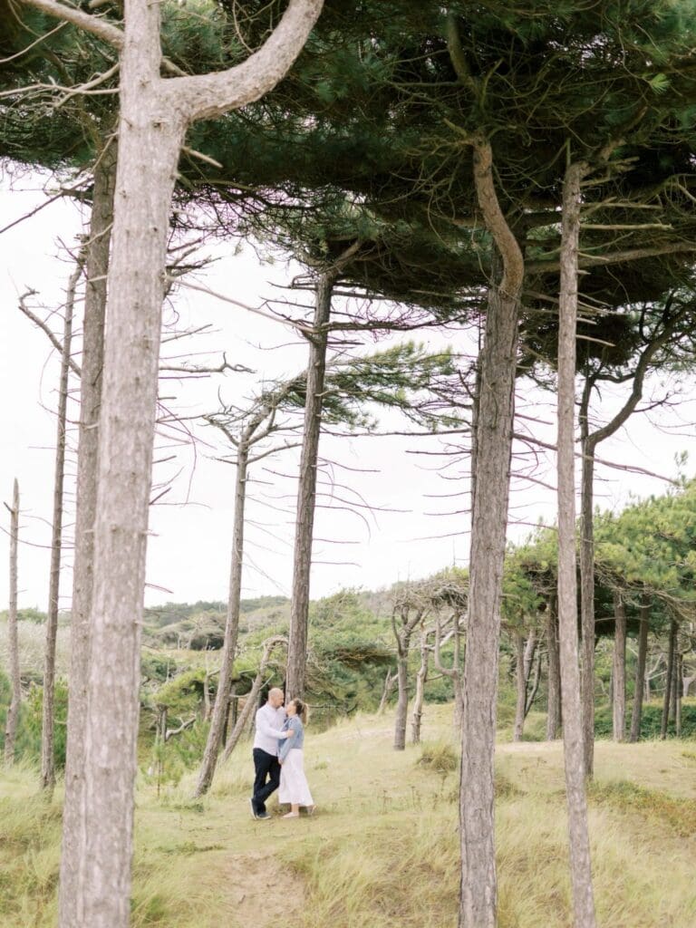 Lauren and fiancé Mark in the trees by the beach captured by Heledd Roberts Photography during their engagement